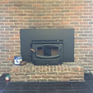 Clean and ready wood stove insert in Chesapeake, VA, professionally vented and mounted within a brick fireplace.