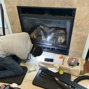 Gas fireplace repair in Virginia Beach, VA showing a technician inspecting the pilot assembly and ignition system for safety and performance.