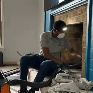 A chimney professional removing creosote from a fireplace before a chimney cleaning.