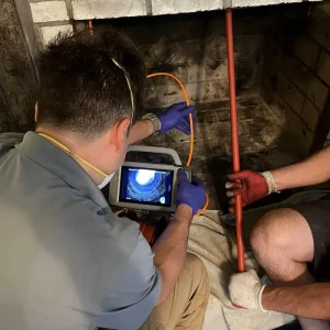 CSIA Certified Chimney Sweep in Virginia Beach verifying chimney cleanliness with inspection camera after rotary chimney cleaning.