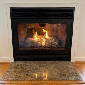 Chesapeake, VA gas fireplace after complete servicing, featuring clean glass, even flame pattern, and functional remote control.