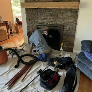 Technician cleaning fireplace glass during chimney sweep in Chesapeake
