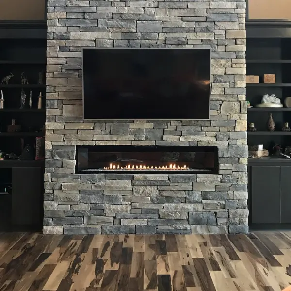 Modern linear gas fireplace installation with custom stone surround and television