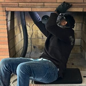 Vacuuming the fireplace smoke shelf during a chimney sweep in Hampton VA using specialized chimney cleaning equipment.