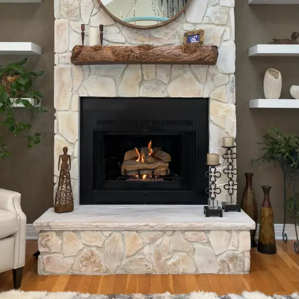 Ventless gas log installation with custom stone fireplace and rustic wood mantel